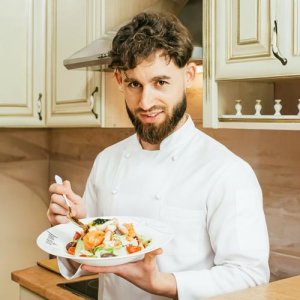 Chef holding a gourmet salad plate.